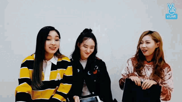 three girls are sitting next to each other and smiling .