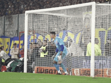 a soccer goalie stands in front of a net with a gatorade advertisement in the background