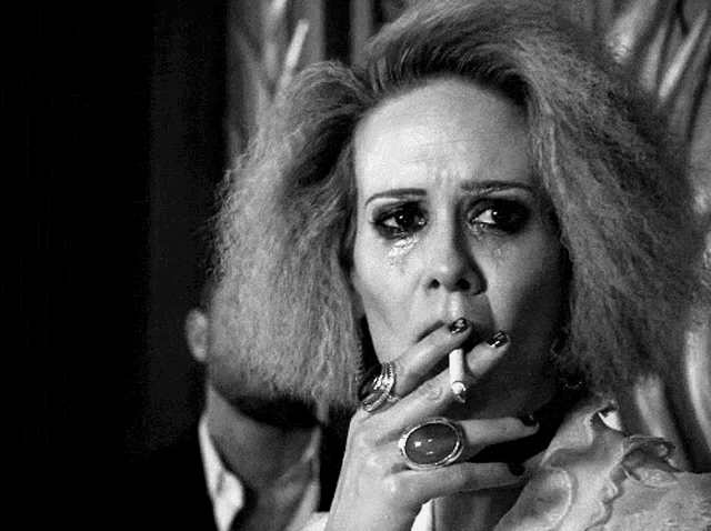 a woman with a ring on her finger smoking a cigarette
