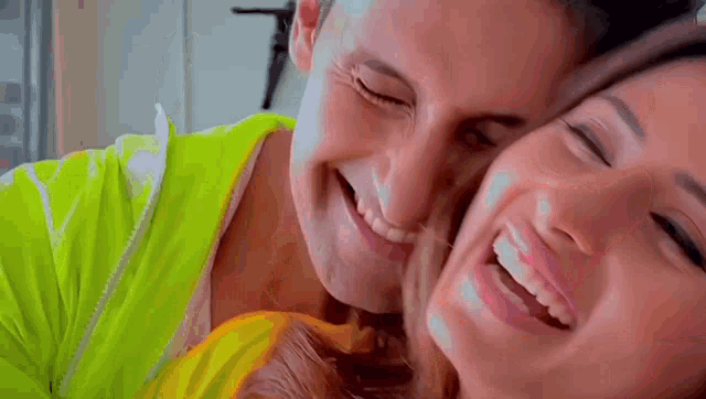 a man and a woman are laughing together and the woman is kissing the man on the cheek .