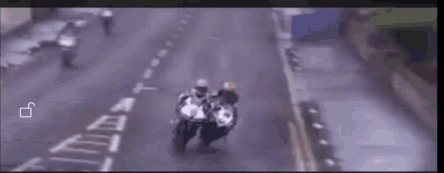 a man is riding a motorcycle down a street with the letter t visible