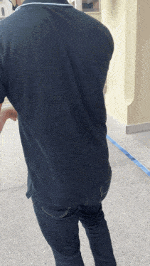 a man wearing a black shirt and jeans is standing on a sidewalk