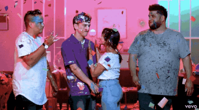 a group of people are standing in a room with confetti falling and the word vevo is on the bottom right
