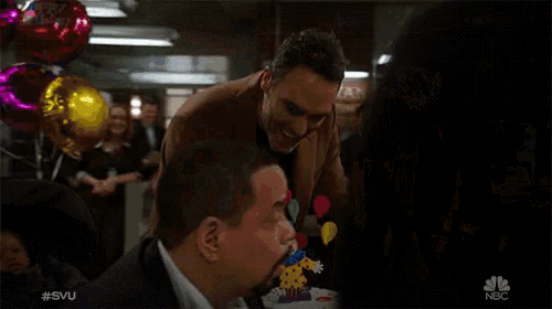 two men celebrate a baby 's birthday with balloons and a cake with a clown on top of it