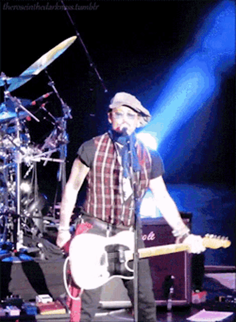 a man singing into a microphone while holding a guitar in front of a marshall amplifier on stage