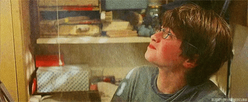 a young boy wearing glasses is looking up at something in a room .