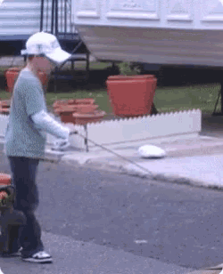 a young boy is playing with a remote control car on the street