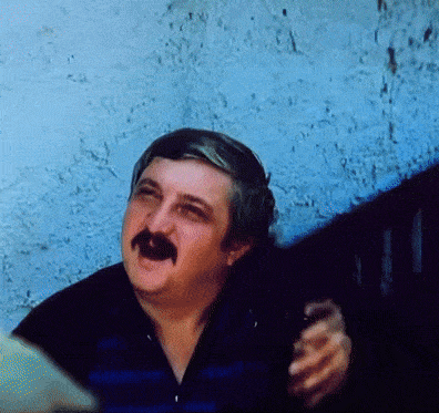 a man with a mustache is holding a bottle of beer