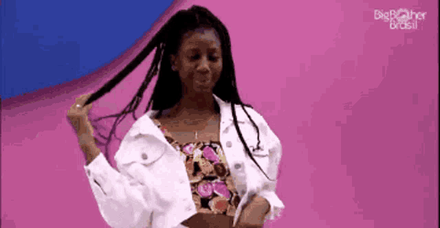 a woman in a white denim jacket is holding her hair