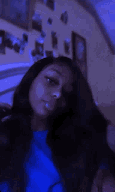 a woman is laying on a bed with her eyes closed and a blue shirt on .