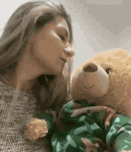 a woman is holding a teddy bear in her arms