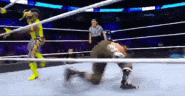 a wrestling match is being played in a ring with a referee .