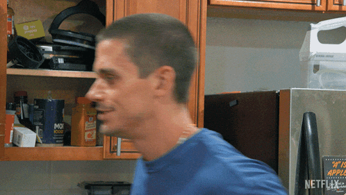 a man in a blue shirt is standing in front of a netflix advertisement