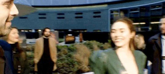 a woman in a green jacket is smiling in front of a crowd of people
