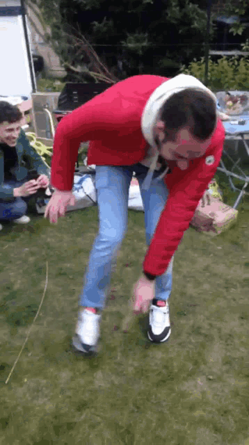a man in a red jacket is standing on a lawn