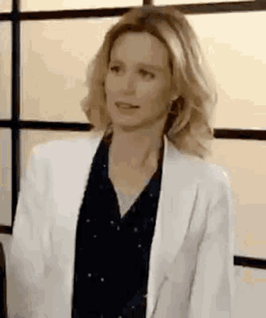 the woman is wearing a white jacket and a black shirt .