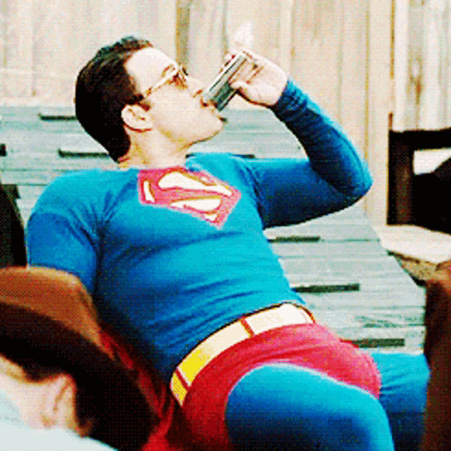 a man in a superman costume drinking a beer