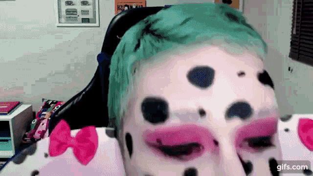 a person with green hair and dalmatian makeup on their face .