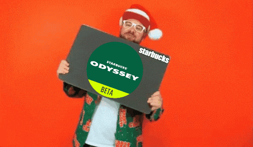 a man wearing a santa hat is holding up a starbucks odyssey beta sign