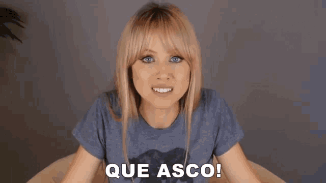 a woman in a grey shirt says que asco in white letters