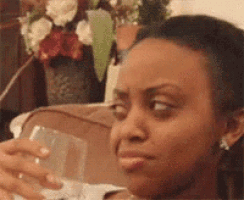 a woman is sitting on a couch holding a glass of water in her hand .