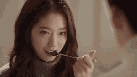 a woman is eating chocolate with a spoon while looking at a man .