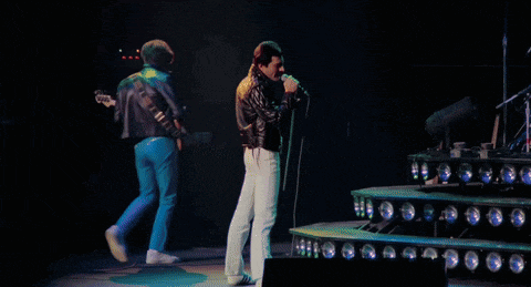 a man in a leather jacket is singing into a microphone on stage