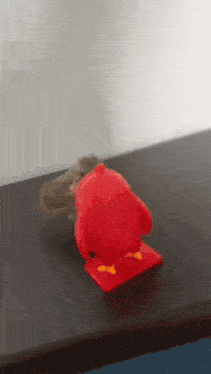 a red angry bird toy is sitting on a table next to a mouse .