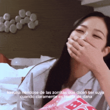 a woman covering her mouth with her hand and the words kazuha riendose de las zorritas