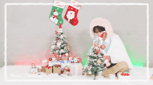 a man in a pink bunny hat is decorating a small christmas tree
