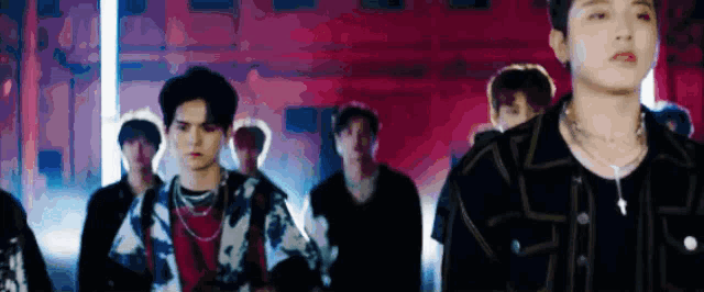 a group of young men are standing in a row in front of a red wall .