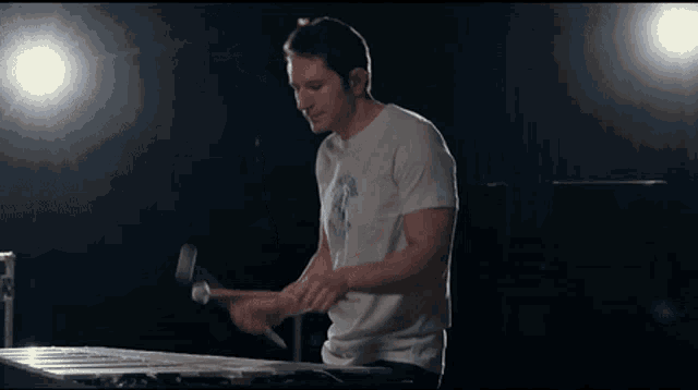 a man in a white shirt is playing a hammer and mallet