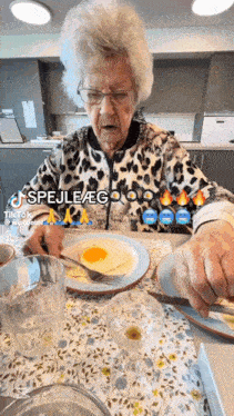 an elderly woman sitting at a table with a plate of food