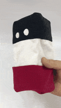 a person is holding a red white and black stuffed object