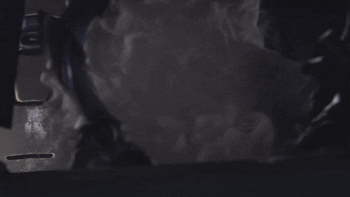 a person is standing in a dark room with smoke coming out of it .