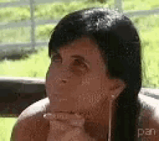 a woman is sitting on a bench with her hand on her chin and looking at the camera .