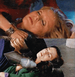 two women are laying down with their eyes closed and one is wearing a green sweater