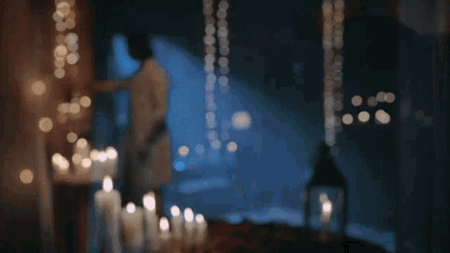 a blurry picture of a man and woman surrounded by candles and lanterns
