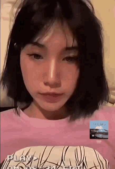 a girl with short hair is wearing a pink shirt and looking at the camera