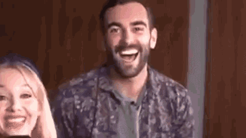 a man and a woman are sitting next to each other and laughing .