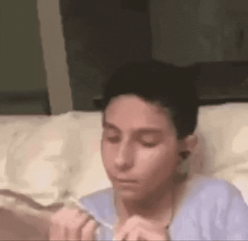 a young boy is laying on a bed eating food with a fork .