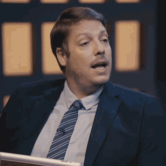 a man in a suit and tie with a microphone on his neck
