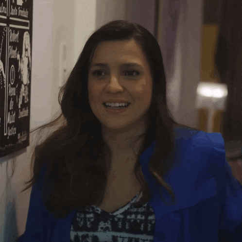 a woman in a blue jacket is smiling in front of a sign that says " robert " on it