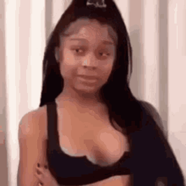 a woman in a black bra is standing in front of a white curtain .