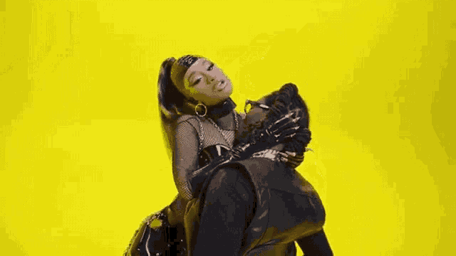 a man is carrying a woman on his back in front of a yellow background .