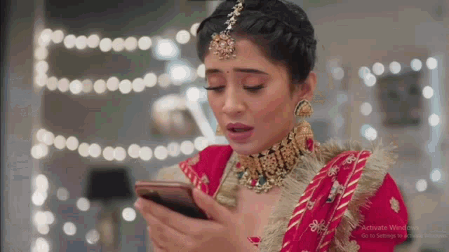 a woman in a red and gold dress is looking at her phone .