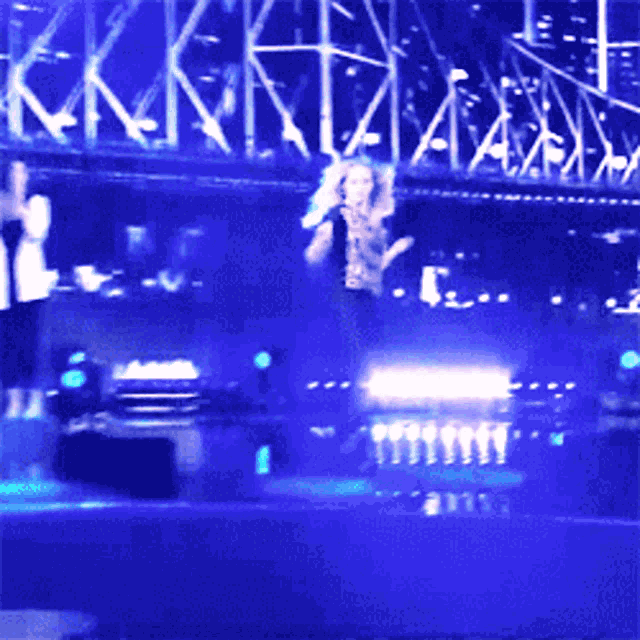 a woman is singing into a microphone on a stage with blue lights
