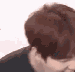 a close up of a person 's face with red hair and a black shirt .