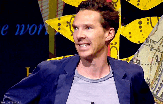 a man wearing a blue jacket and a grey shirt is smiling in front of a sign that says the lost smiles