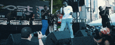 a man taking a picture of a group of people on a stage with a sign that says post